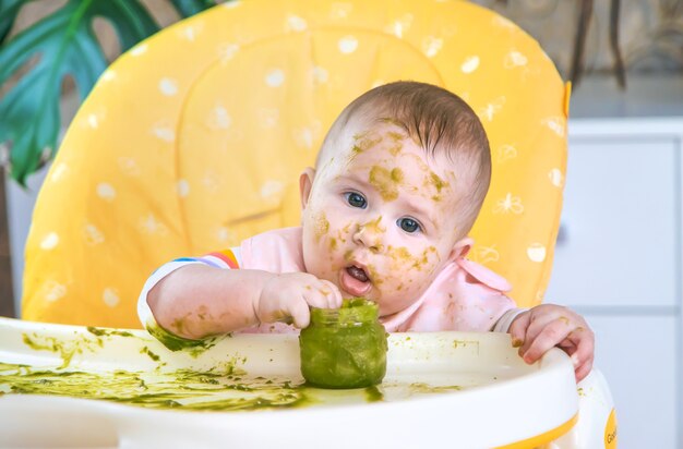 Kleines Baby isst selbst Brokkolipüree. Selektiver Fokus. Menschen.