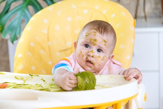 Kleines Baby isst selbst Brokkolipüree. Selektiver Fokus. Menschen.