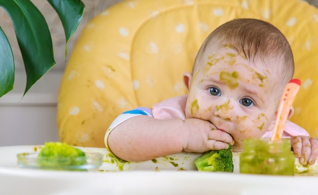 Kleines Baby isst selbst Brokkolipüree. Selektiver Fokus. Menschen.