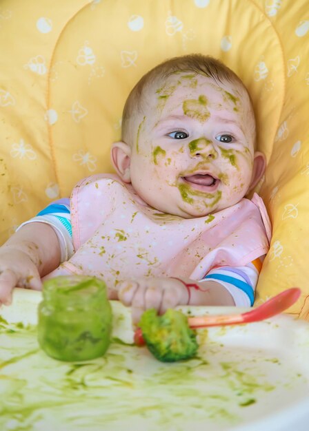 Kleines Baby isst selbst Brokkolipüree. Selektiver Fokus. Menschen.