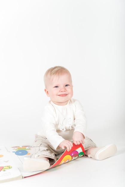 Kleines Baby mit dem Buch auf dem Weiß