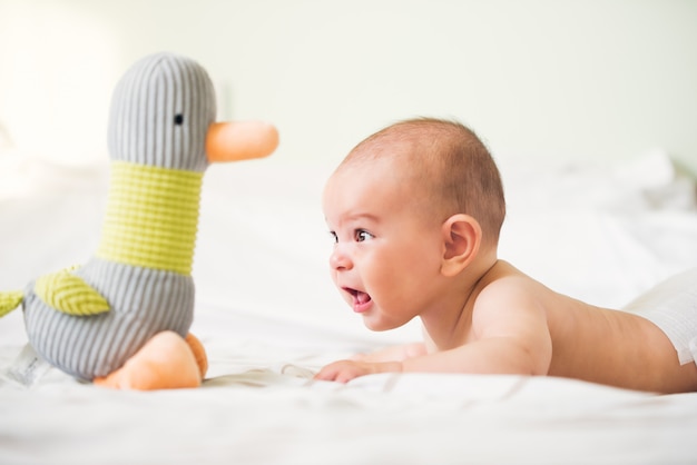 Kleines Baby neugeboren auf hellem luftigem Hintergrund auf dem Bett mit einer Spielzeugente