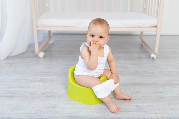 Kleines Baby sitzt auf einem Töpfchen, Babytoilette, Platz für Text