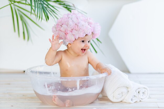 kleines Baby wäscht in einem Becken mit Schaum