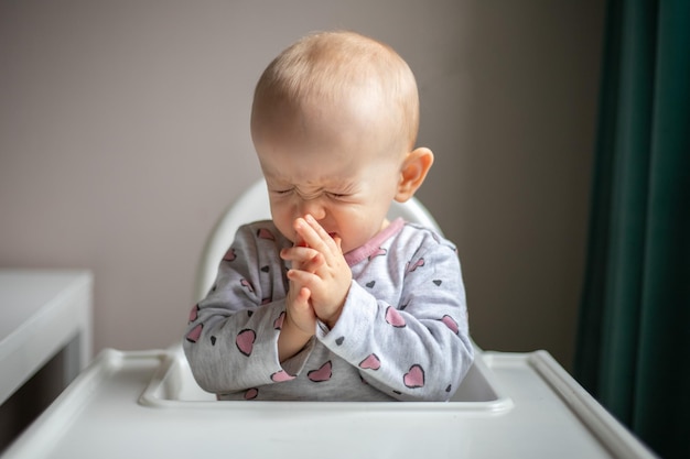 Kleines Baby will nicht erste Beikost essen Verärgertes Kind am Hochstuhl