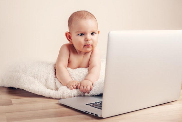 Kleines Babykindarbeitsspielen, lernend auf dem Laptop