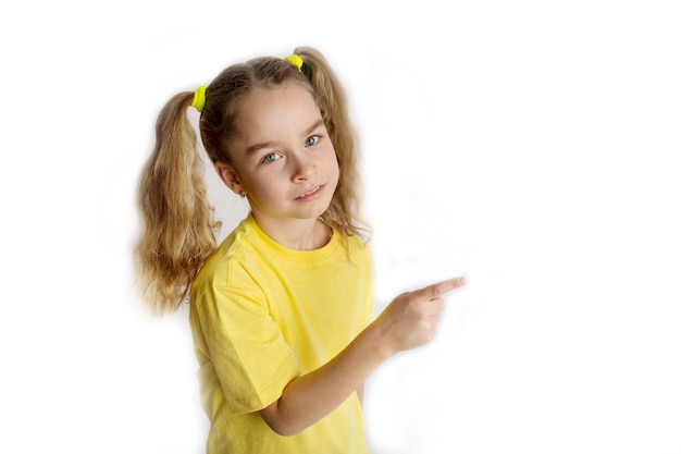 Kleines blondes Mädchen 8-9 Jahre alt in einem gelben T-Shirt macht Gesten, hebt die Finger, isoliert auf einem weißen Hintergrund Kinder-Studioporträt. Lifestyle-Konzept der Kindheit. Foto in hoher Qualität