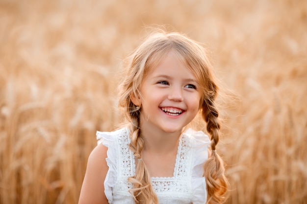 Kleines blondes Mädchen geht in einem Sommerweizenfeld