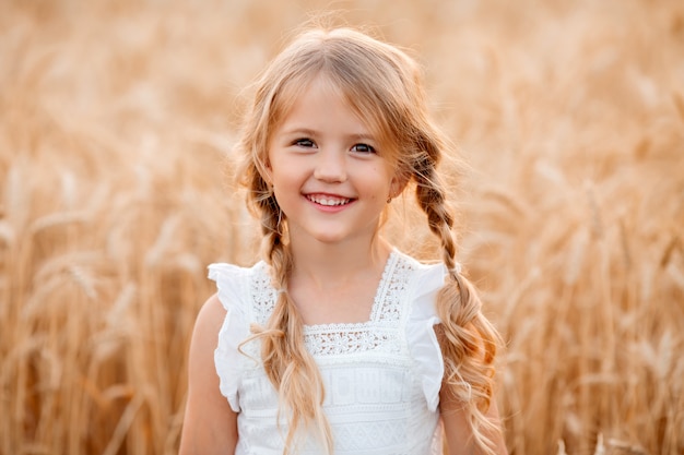 Kleines blondes Mädchen geht in einem Sommerweizenfeld