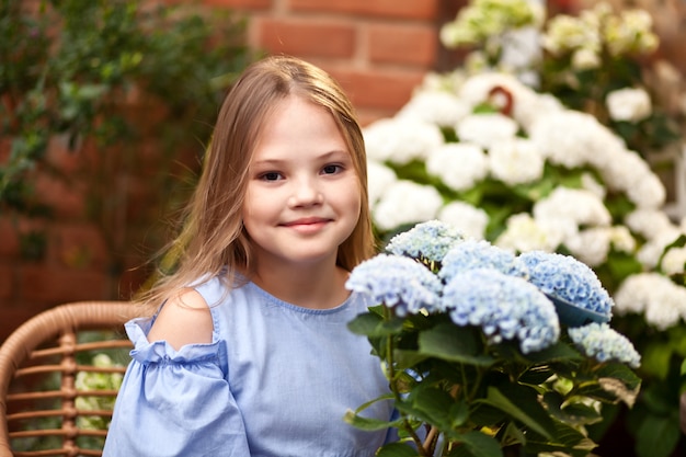 Kleines blondes Mädchen im blauen Kleid mit Blumen