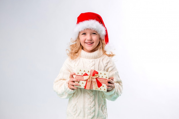 kleines blondes Mädchen im Sankt-Hut, der Geschenkbox hält