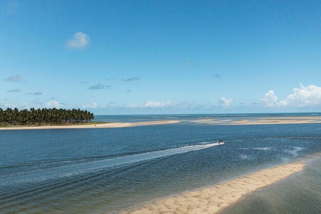 Kleines Boot, das dort segelt, wo der Fluss auf das Meer trifft