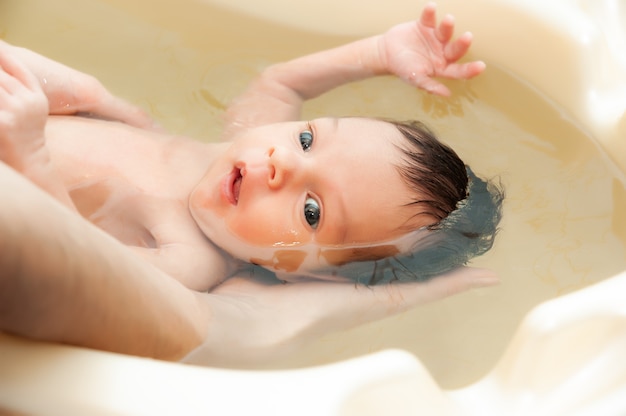 Kleines charmantes Mädchen badet in warmem Wasser in der Badewanne