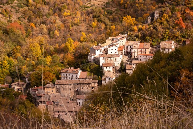 Kleines Dorf in herbstlicher Landschaft mit bunten Bäumen in Italien