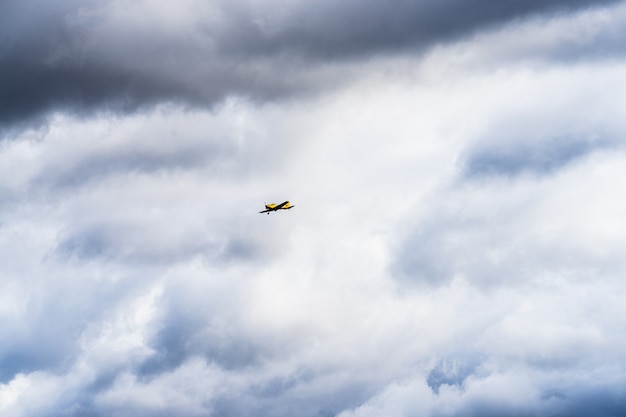 Kleines einmotoriges Flugzeug, das im englischen bewölkten Himmel fliegt