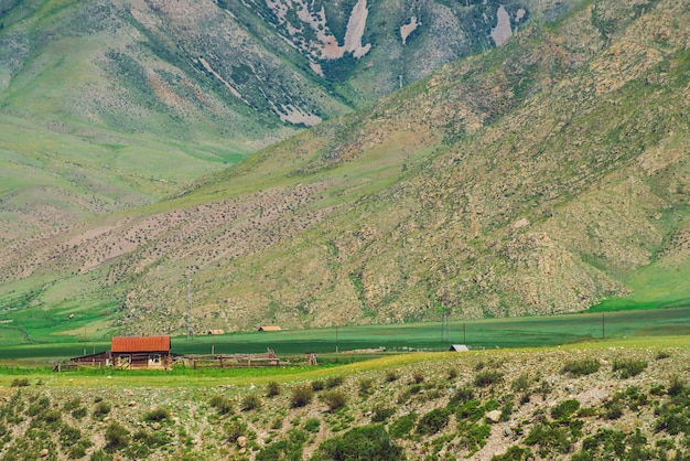 Kleines einsames Dorfhaus mit rotem Dach nahe Abgrund nahe Fuß des Berges.