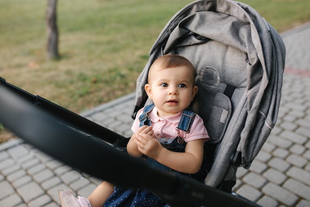 Foto kleines entzückendes baby im kinderwagen draußen sommerspaziergang mit der familie im park