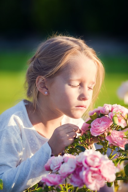 Kleines entzückendes Mädchen, das draußen bunte Blumen riecht