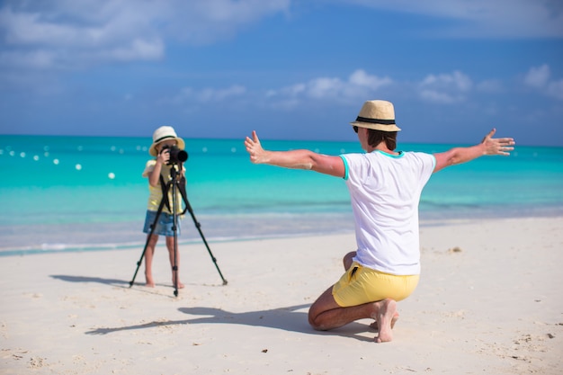 Kleines entzückendes Mädchen, das Foto von ihrem jungen Vater am exotischen Strand macht