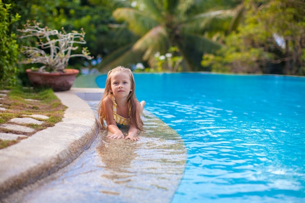 Kleines entzückendes Mädchen im Swimmingpool betrachtet Kamera