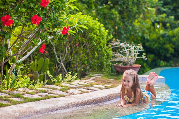 Kleines entzückendes Mädchen im Swimmingpool betrachtet Kamera