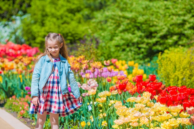 Kleines entzückendes Mädchen in blühendem Tulpengarten