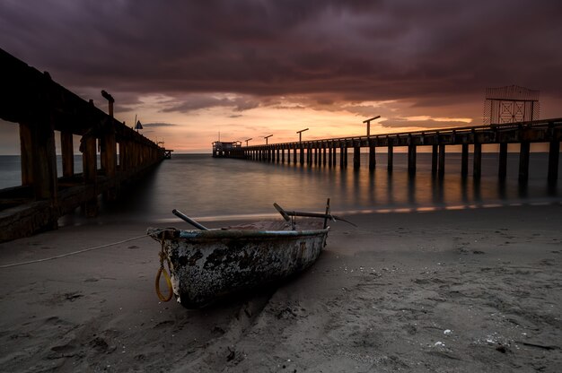 Kleines Fischerboot aus Holz am Strand mit Sonnenuntergangsbeleuchtung.