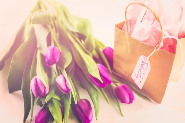 Kleines Geschenk und lila Tulpen zum Muttertag.