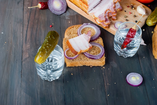 Kleines Glas mit russischem Wodka, Sandwich mit geräuchertem Speck und Salzgurke