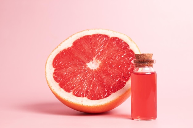 Kleines Glasfläschchen mit ätherischem Aromaöl mit frischer Grapefruitscheibe