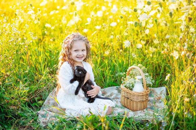 Kleines glückliches Mädchen auf dem Feld mit Blumen