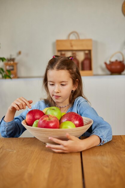 Kleines glückliches Mädchen hält Schale mit Früchten in der Küche zu Hause gesunder Kindersnack Gesundes Essen zu Hause liebt Obst und Vitamine