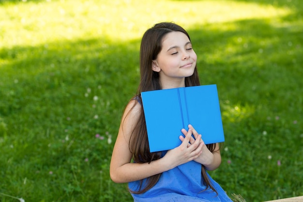 Kleines glückliches Mädchen liest Buch im Freien sonnigen Tag Happy End Konzept
