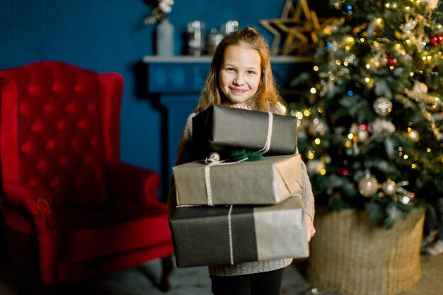 Kleines glückliches schönes Mädchen hält Weihnachtsgeschenke