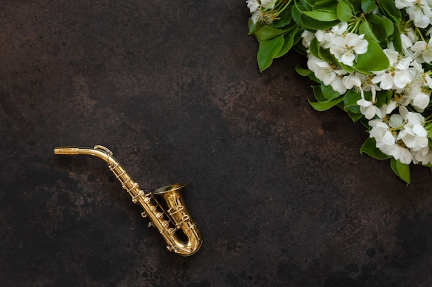 Kleines goldenes Saxophon und blühende Apfelbaumaste.