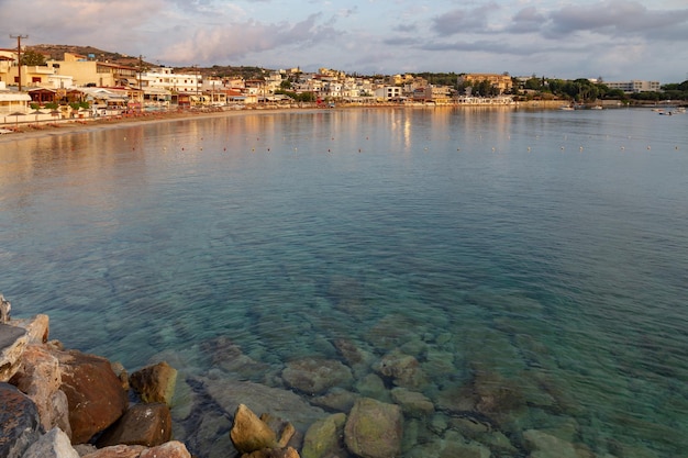 Kleines griechisches Dorf am Meer mit weißen Häusern und Hügeln im Hintergrund bei Sonnenaufgang Kreta Griechenland