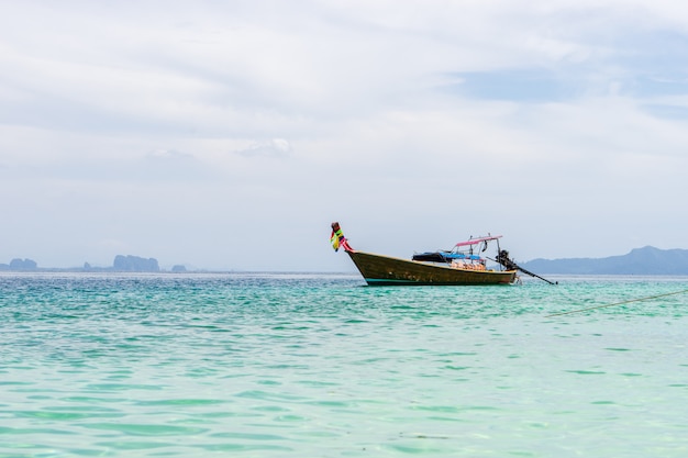 Kleines hölzernes touristisches boot, das auf dem strand mit ansicht des weißen bewölkten himmels verankert