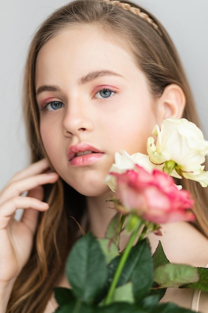 Kleines hübsches Mädchen in Rosa hält den Strauß Rosen Schließen Sie die Blumen und das Gesicht Schönes kleines Mädchen mit Blumen
