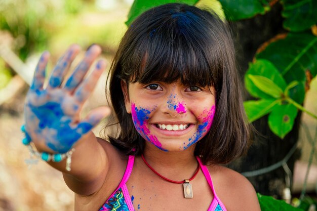 Kleines indisches Mädchen malte ihr Gesicht mit rosa und blauen Farben