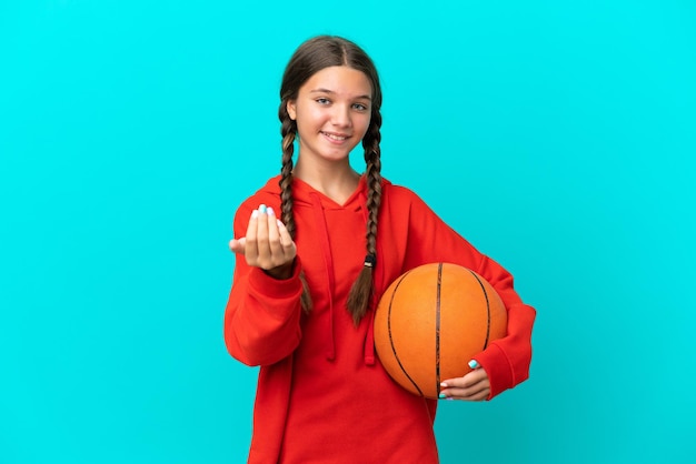 Kleines kaukasisches Mädchen, das Basketball spielt, isoliert auf blauem Hintergrund, der einlädt, mit der Hand zu kommen. Glücklich, dass du gekommen bist
