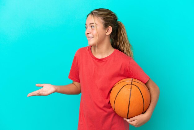 Kleines kaukasisches Mädchen, das Basketball spielt, isoliert auf blauem Hintergrund mit überraschtem Ausdruck, während es zur Seite schaut