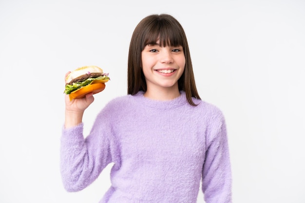 Kleines kaukasisches Mädchen, das einen Burger über isoliertem Hintergrund hält und viel lächelt