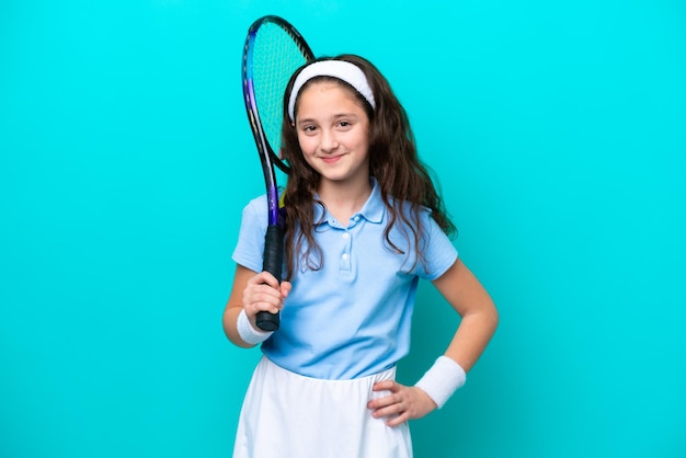 Kleines kaukasisches Mädchen, das Tennis spielt, isoliert auf blauem Hintergrund, lächelt viel