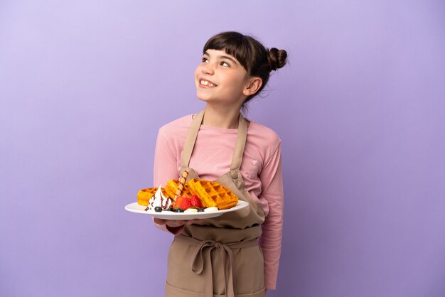 Kleines kaukasisches Mädchen, das Waffeln lokalisiert hält