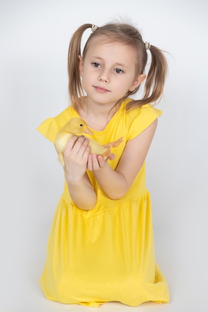 Kleines kaukasisches Mädchen im Vorschulalter, das ein süßes Entlein in den Händen hält