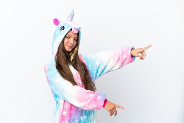 Kleines kaukasisches Mädchen mit Einhornpyjama isoliert auf weißem Hintergrund, das mit dem Finger zur Seite zeigt und ein Produkt präsentiert