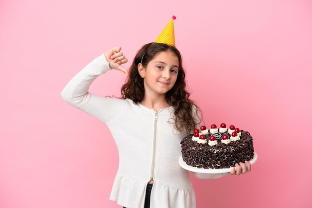 Kleines kaukasisches Mädchen mit Geburtstagstorte isoliert auf rosa Hintergrund stolz und selbstzufrieden