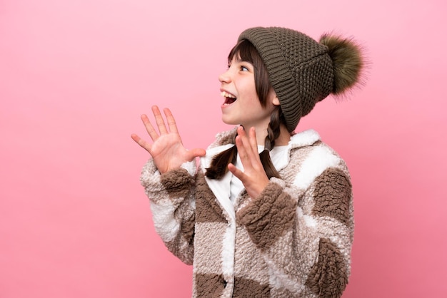 Kleines kaukasisches Mädchen mit Winterjacke isoliert auf rosa Hintergrund mit überraschendem Gesichtsausdruck