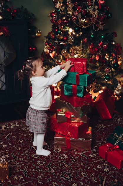 Kleines kaukasisches Mädchen und Weihnachtsgeschenke. Weihnachtsbaum.