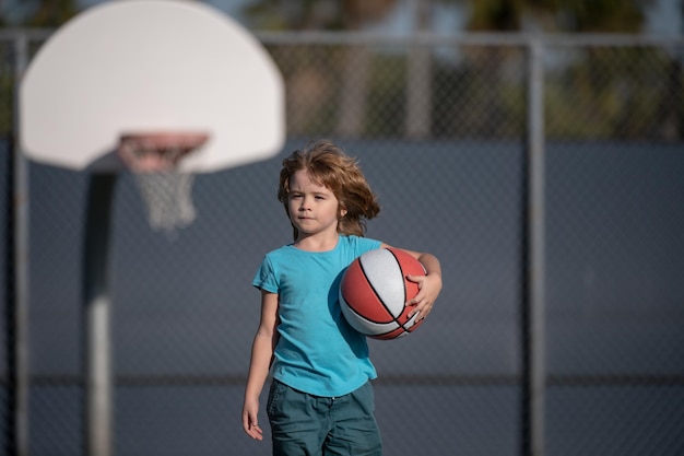 Kleines kaukasisches Sportkind, das Basketball mit Ball spielt